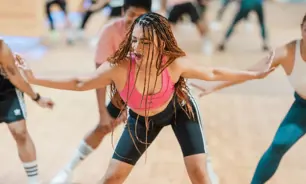 GNWomen leading a high-energy Zumba class at GymNation, dancing in a colorful studio with other participants in the background