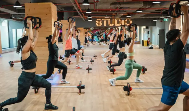 مجموعة من الأشخاص يؤدون تمارين ليس ميلز بودي بامب في جيمنيشن دبي، باستخدام القضبان