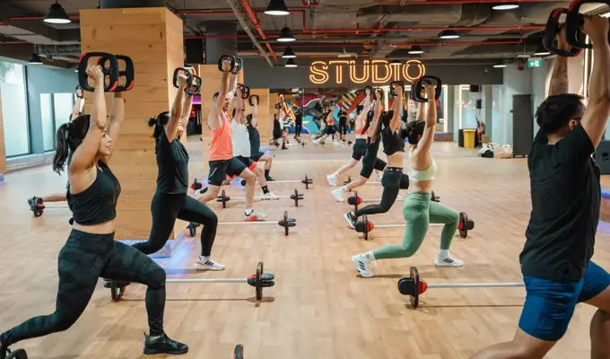 GN-مجموعة من الأشخاص يؤدون تمارين ليس ميلز بودي بامب في جيمنيشن دبي، باستخدام القضبان